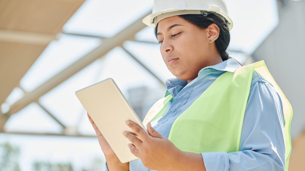 Female construction worker checking safety information on a tablet for a Korean construction safety lesson.