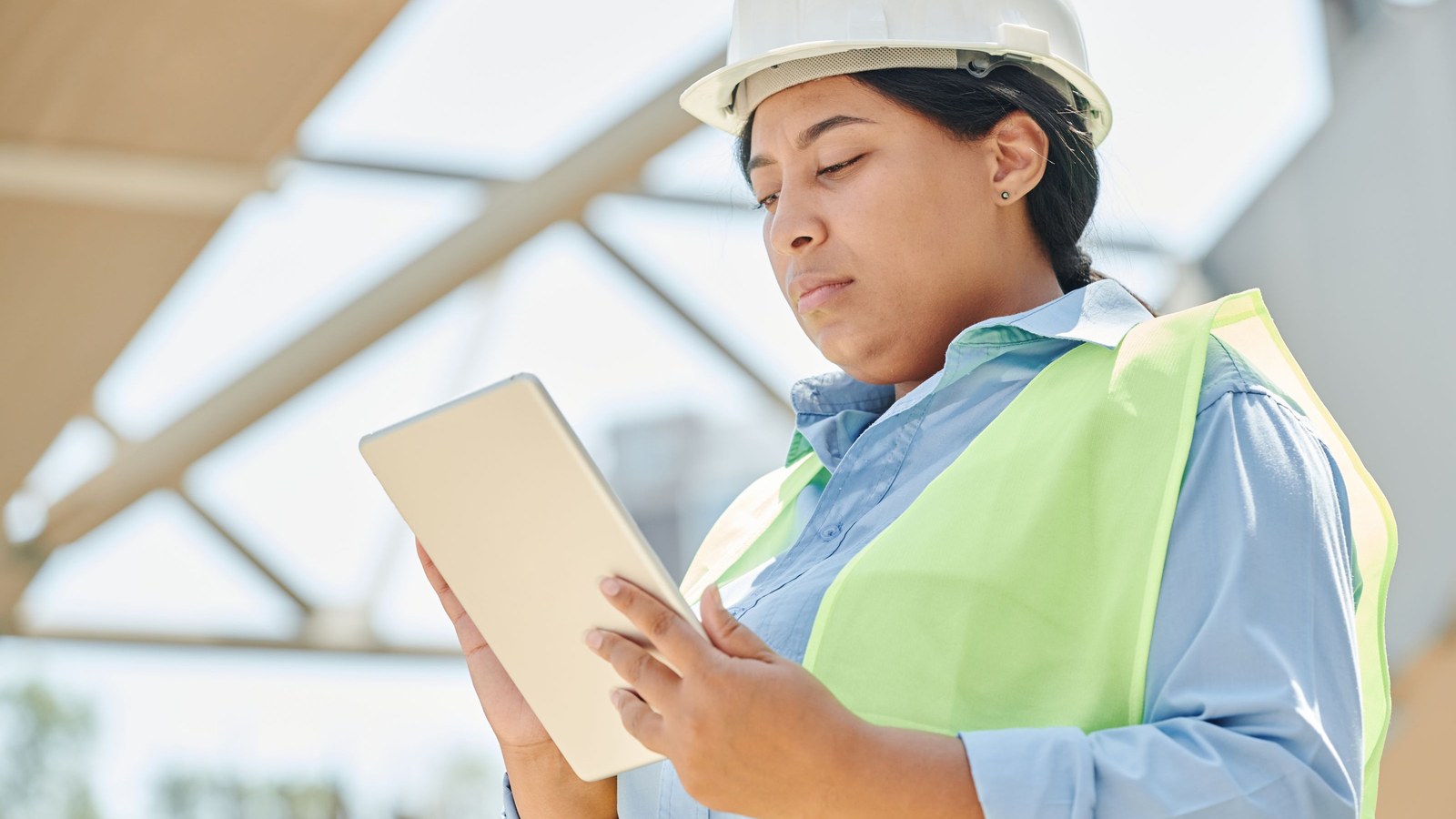 Female construction worker checking safety information on a tablet for a Korean construction safety lesson.